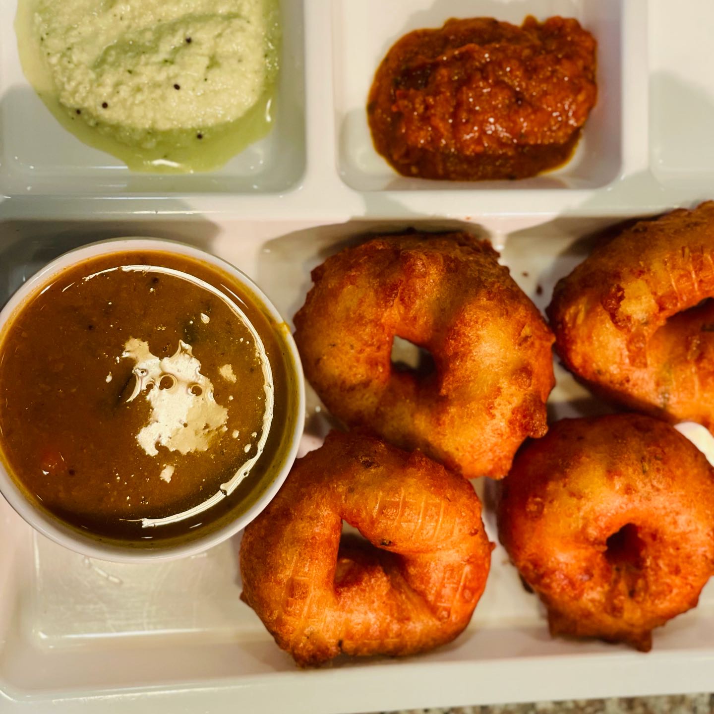 Deep fried split black gram dough served with chutneys and sambar