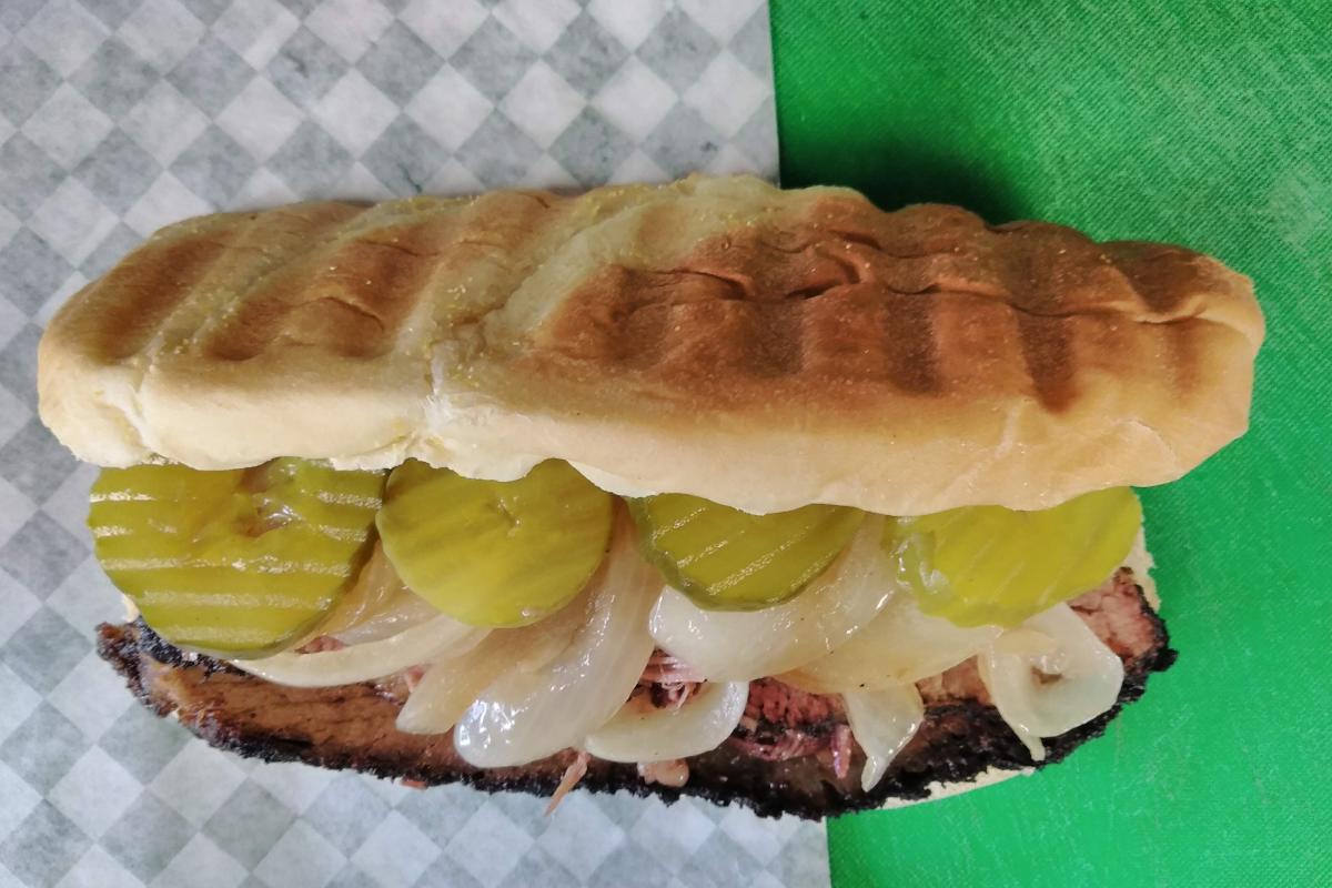 Slow smoked beef brisket topped with mayo chipotle sauce, sautéed onions, dill pickles on a Pub Bun, side of BBQ sauce and choice of small coleslaw or fries. - Raining BBQ & Grill restaurant in Beaverton, OR