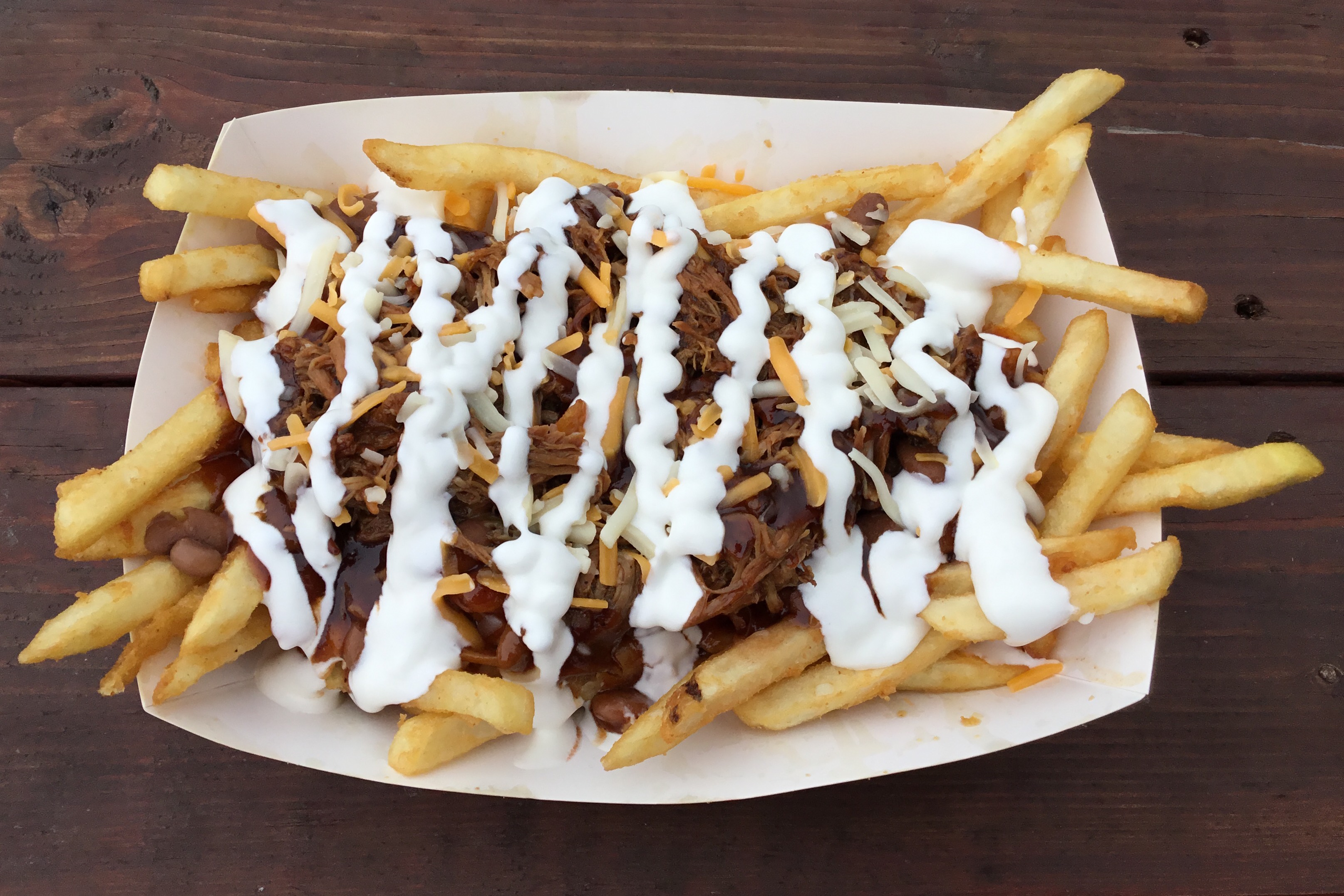 Crispy french fries topped with shredded cheese, pinto beans, smoked pulled pork, BBQ sauce and sour cream.