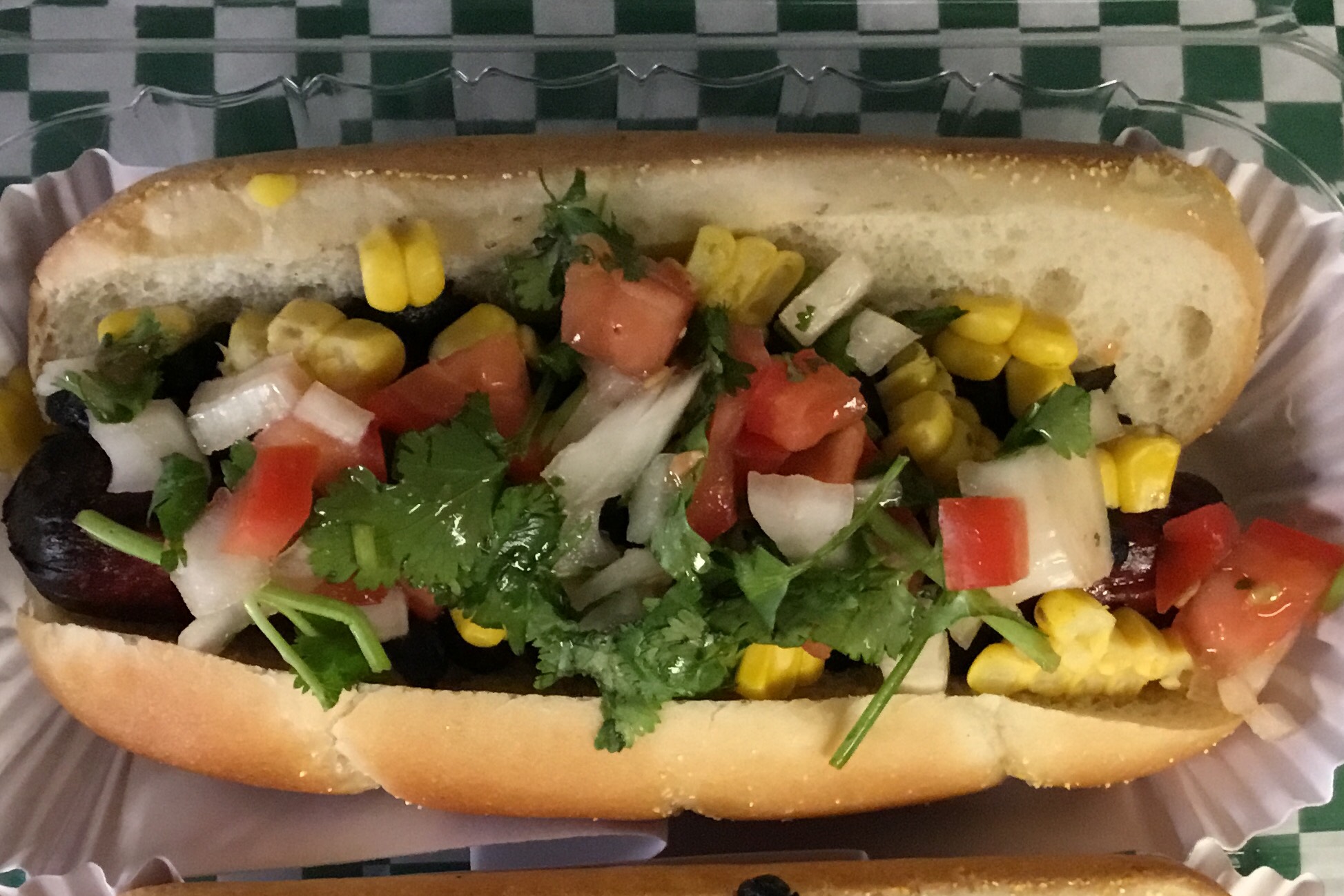 Beef frank in a Pioneer Roll, mayo chipotle sauce, grilled corn, black beans and onions, tomatoes, cilantro mix.