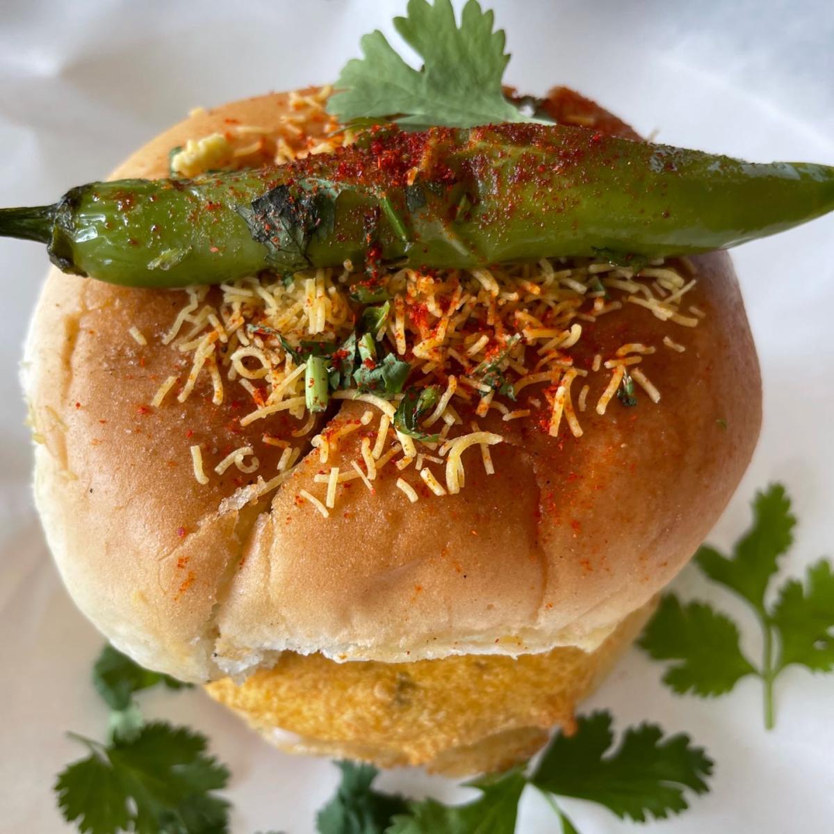 Dish of a deep fried potato dumpling placed inside a bread bun. - Desi Bites restaurant in Hillsboro, OR