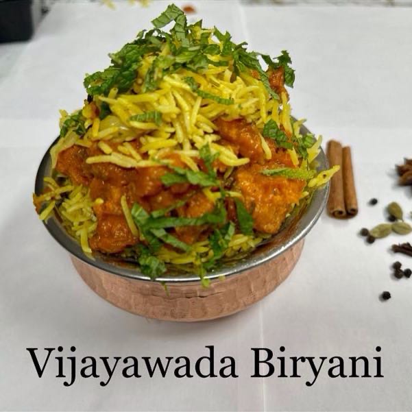 Succulent pieces of chicken cooked in a fiery blend of Andhra spices, layered with aromatic basmati rice, offering a spicy and flavorful culinary experience reminiscent of the vibrant cuisine of Vijayawada. Served with raita.