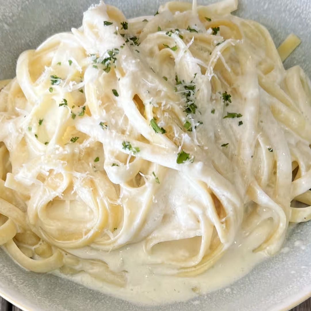 Fettuccini in a creamy Parmesan sauce topped with fine herbs and grated Reggiano served with grilled bread.