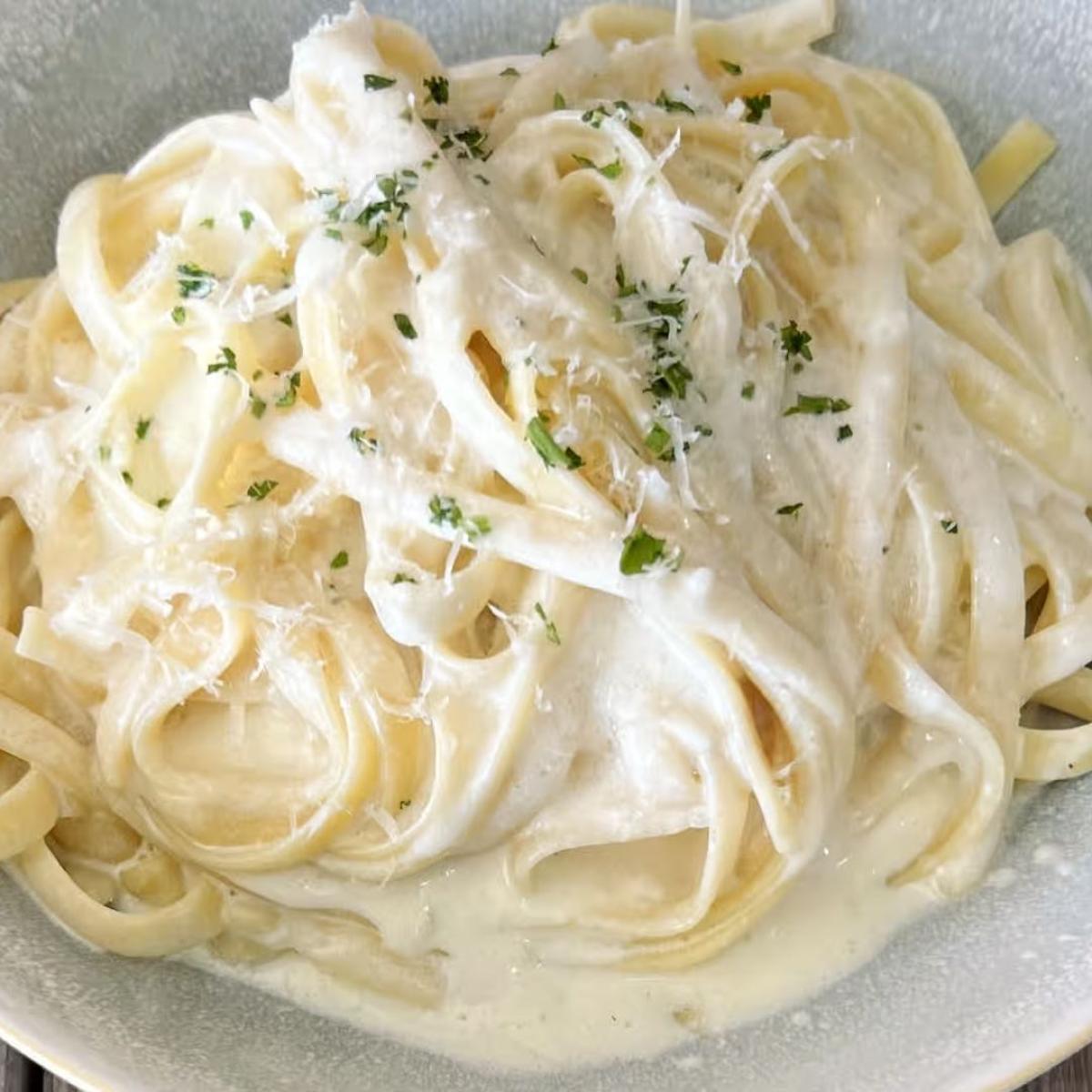 Fettuccini in a creamy Parmesan sauce topped with fine herbs and grated Reggiano served with grilled bread. - FG Amore restaurant in Forest Grove, OR