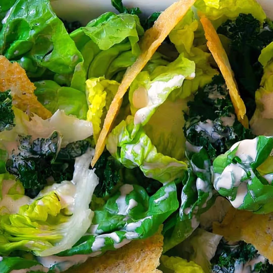 Baby jems, seasonal greens, warm focaccia croutons, Parmesan frico, fin herbs, and lemon caesar dressing.