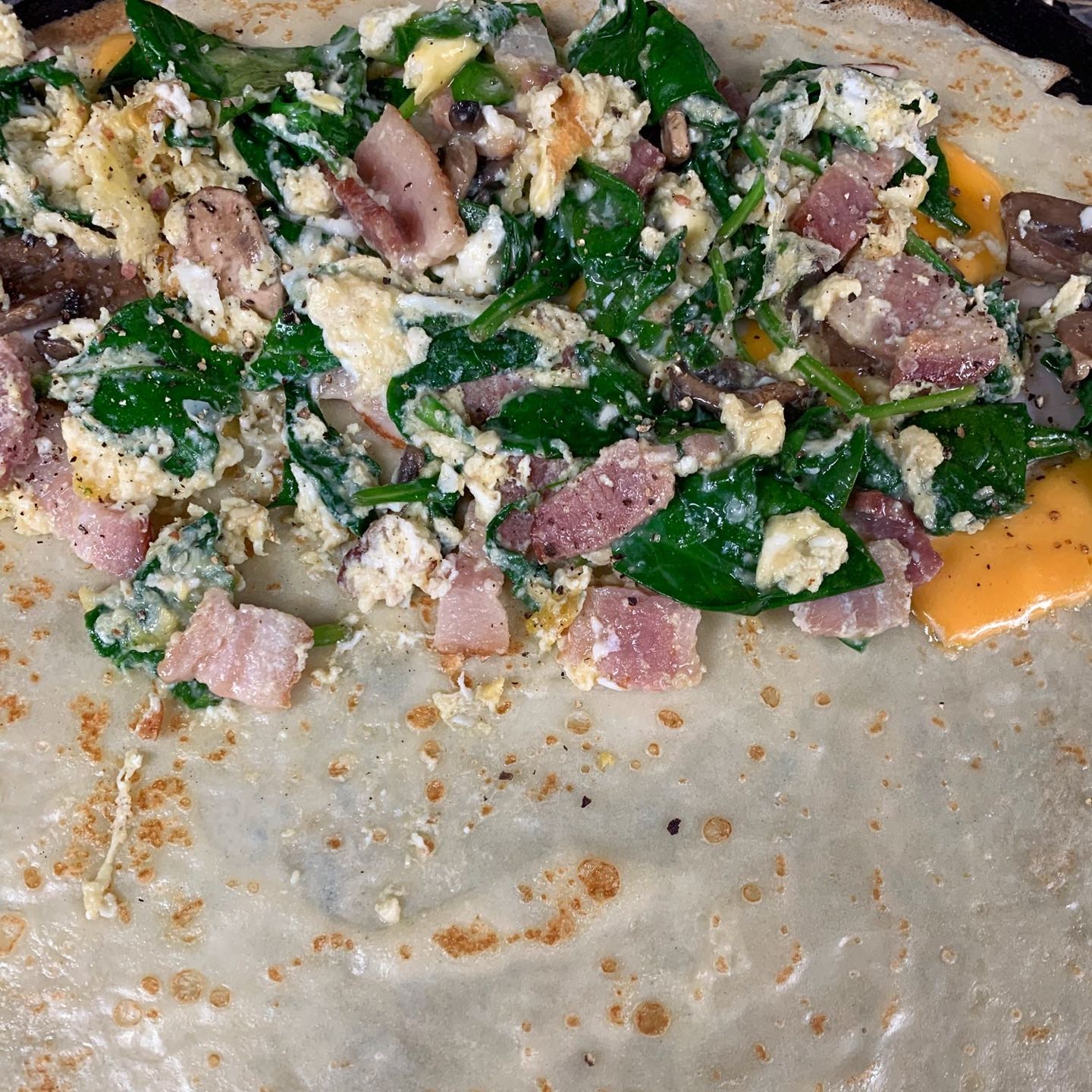 Scrambled egg, bacon bites (optional), cheddar cheese, sauteed mushrooms, spinach, salt & pepper.